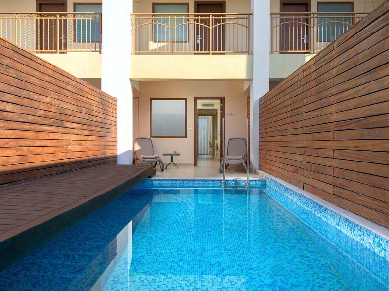 Schmaler blauer Pool zwischen Holzwänden mit Stühlen und Tür zum Haus im Hintergrund.