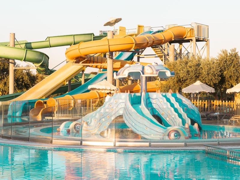 Wasserrutschen im Schwimmbad bei sonnigem Wetter mit Blick auf Liegestühle.