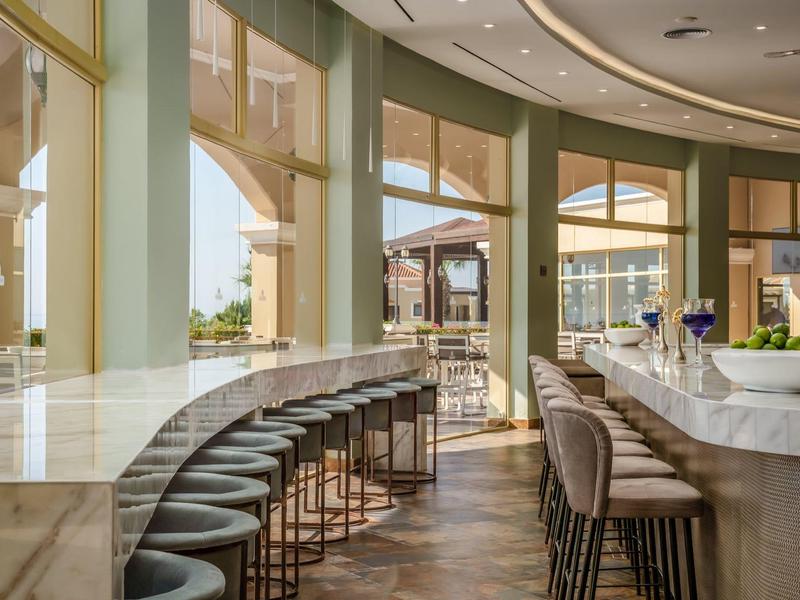 Heller, moderner Bar- und Restaurantbereich mit hohen Stühlen und Fensterblick.