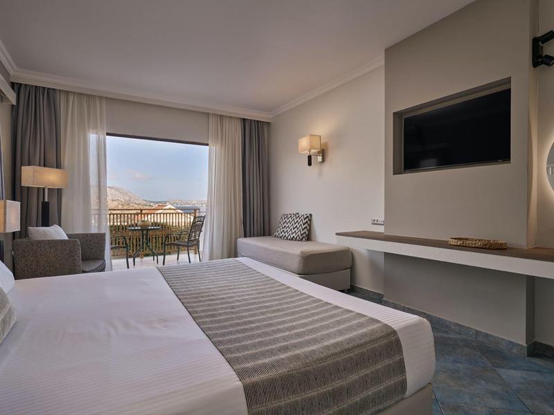 Modernes Hotelzimmer mit großem Bett, Sitzbereich und Balkon mit Aussicht.