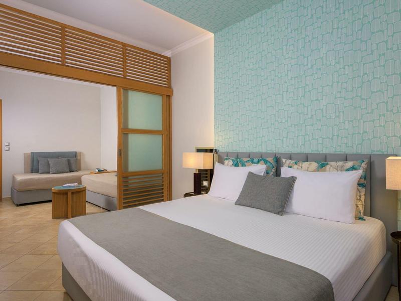 Modernes Hotelzimmer mit angrenzendem Wohnzimmer, elegant eingerichtet mit Bett und Sofa.