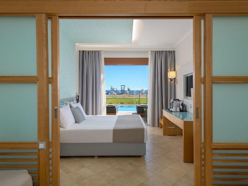 Modernes Hotelzimmer mit Doppelbett, Schreibtisch und Blick auf den Pool und die Skyline.