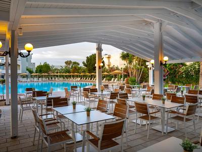 Terrazza coperta con tavoli e sedie accanto a una piscina dell'hotel.
