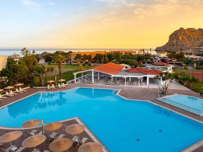 Piscina dell'hotel con ombrelloni e lettini, montagna pittoresca sullo sfondo al tramonto.