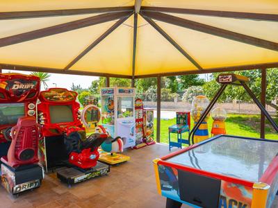 Spielhalle mit Airhockey-Tisch und mehreren Arcade-Spielen unter einem Sonnendach.