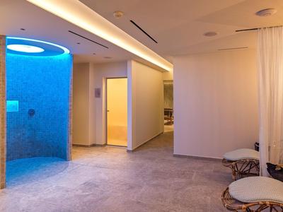 Moderner Wellnessbereich mit blau beleuchtetem Dampfraum und gemütlichen Sitzgelegenheiten.