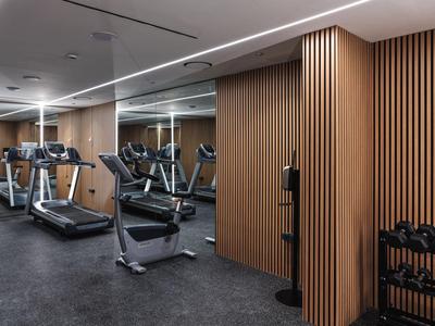 Palestra moderna con tapis roulant, manubri e pareti con pannelli in legno.