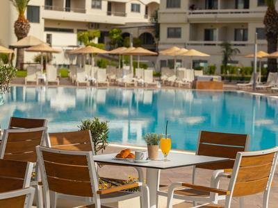 Ein Außenpoolbereich mit Tischen, Stühlen und Drinks in einem Hotel.