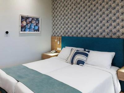 Modernes Hotelzimmer mit großem Bett, blauem Kopfteil und dekorativem Wandmuster.