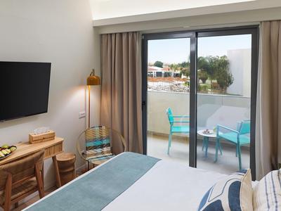 Gemütliches Hotelzimmer mit Blick auf einen Balkon und einen Tisch mit Stühlen.