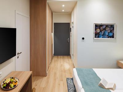 Modern eingerichtetes Hotelzimmer mit TV, Holzmöbeln, Bett und Badezimmertür