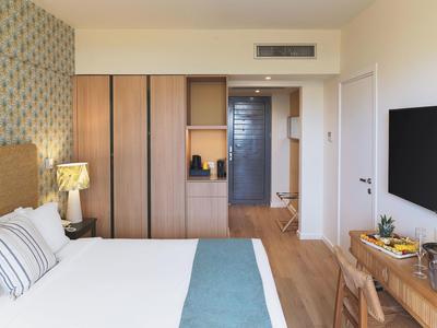 Modernes Hotelzimmer mit großem Bett, Holzmöbeln und Fernseher an der Wand.