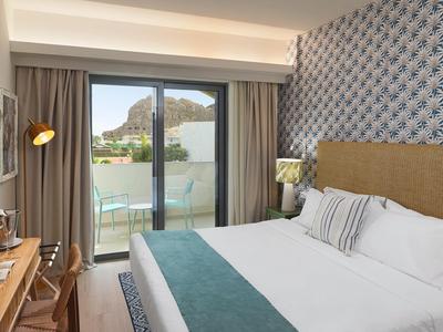 Modernes Hotelzimmer mit großem Bett, Balkon und Bergblick.