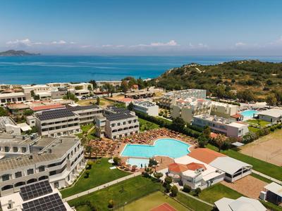 Hotelanlage mit mehreren Gebäuden, Pool und Blick aufs Meer im Hintergrund.