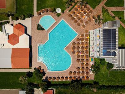 Luftaufnahme eines Hotels mit zwei Poolbereichen und umliegenden Liegestühlen.