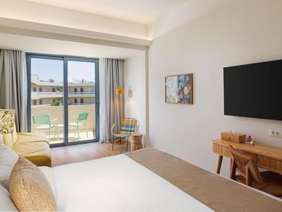 Modernes Hotelzimmer mit Doppelbett, Balkon und Schreibtisch mit Fernseher.