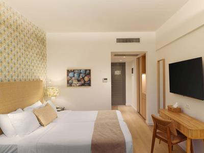 Modern eingerichtetes Hotelzimmer mit Doppelbett, Fernseher an der Wand und Schreibtisch.