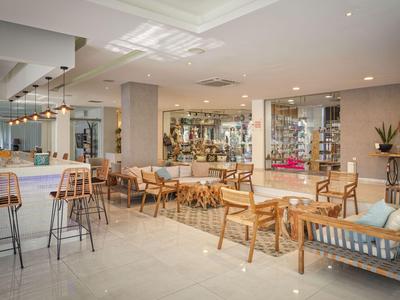 Heller, moderner Hotel-Loungeraum mit Stühlen, Tischen und Barhockern aus Holz und Metall.