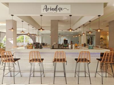 Modernes Hotelbar-Interieur mit fünf Holzstühlen, hängenden Lampen und einem großen Fenster.