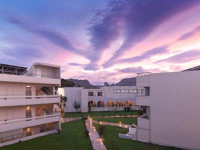 Edificio di hotel moderno con cortile e sentieri sotto un cielo al tramonto viola