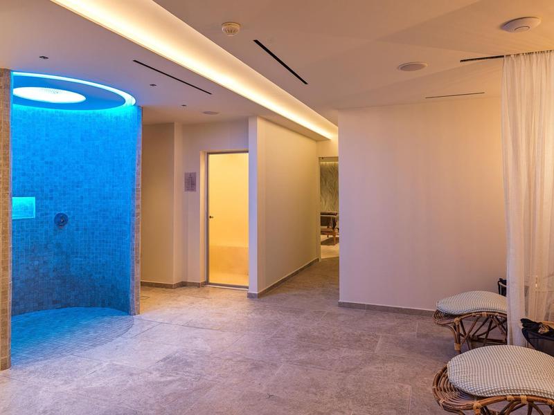 Moderner Wellnessbereich mit blau beleuchtetem Dampfraum und gemütlichen Sitzgelegenheiten.