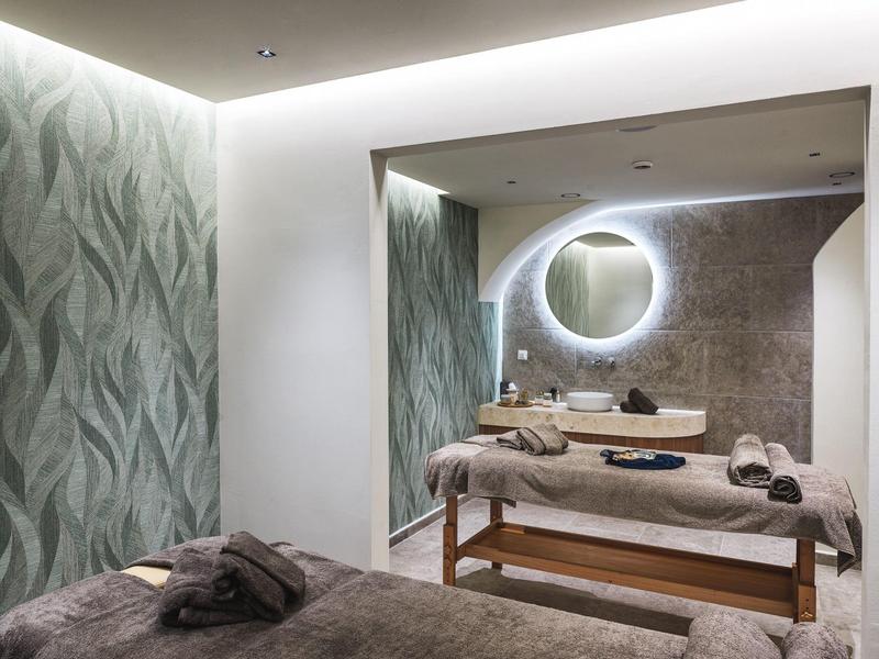 Modern eingerichteter Massageraum mit gedämpftem Licht und runden Spiegeln.