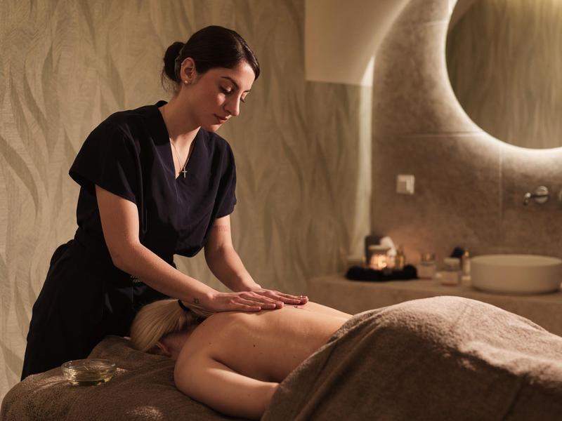 Frau erhält Massage in entspannendem Spa mit warmem Licht und schlichter Einrichtung.