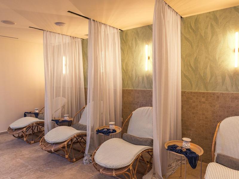 Gemütlicher Wellnessbereich mit Liegen und Vorhängen für Privatsphäre.