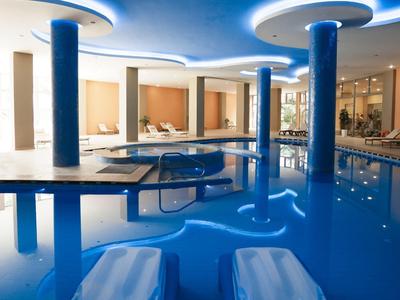 Binnenzwembad met moderne verlichting en ligstoelen in een strak hotel