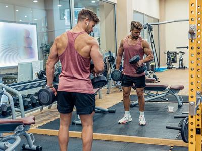 Uomo che solleva pesi davanti a uno specchio in una palestra moderna.