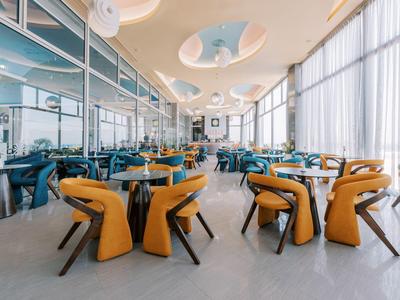 Ristorante moderno con sedie colorate e curve e grandi finestre che lasciano entrare molta luce naturale.