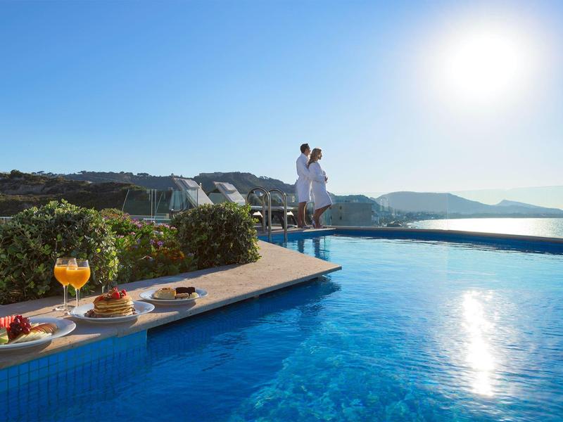 Stel geniet van het uitzicht bij het zwembad met snacks en drankjes bij zonnig weer