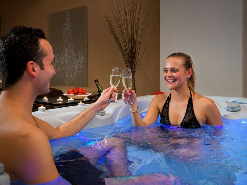 Stel geniet samen van een ontspannend moment in een bubbelbad, proostend met champagneglazen.
