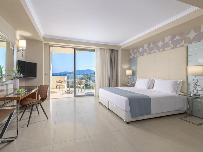Moderne hotelkamer met groot bed en balkon met uitzicht op zee.