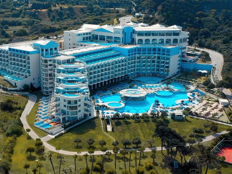 Gran hotel con varias piscinas rodeado de áreas verdes y jardines.