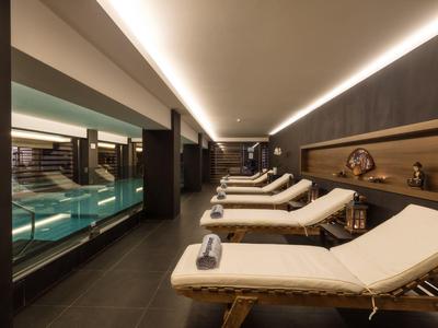 Moderner Ruhebereich mit Liegestühlen und Indoor-Pool in einem Wellnesshotel.