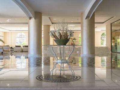 Jasna lobby hotelowa z marmurową podłogą, dwoma kolumnami i kwiatową dekoracją na środku