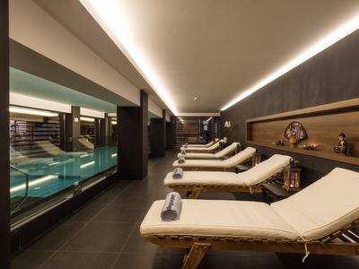 Strefa relaksu z leżakami obok krytego basenu w hotelowym spa.