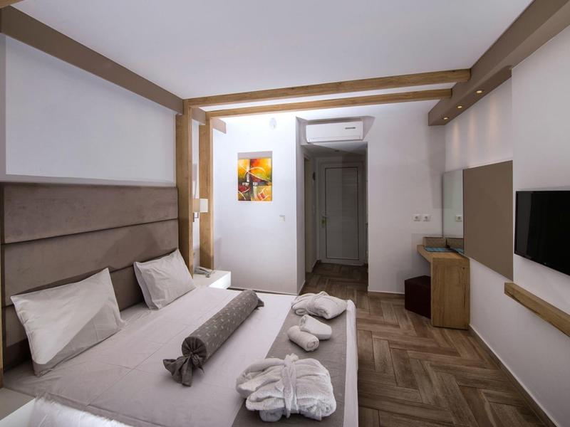 Camera d'hotel moderna con letto matrimoniale, TV e accessori da bagno in colori neutri.