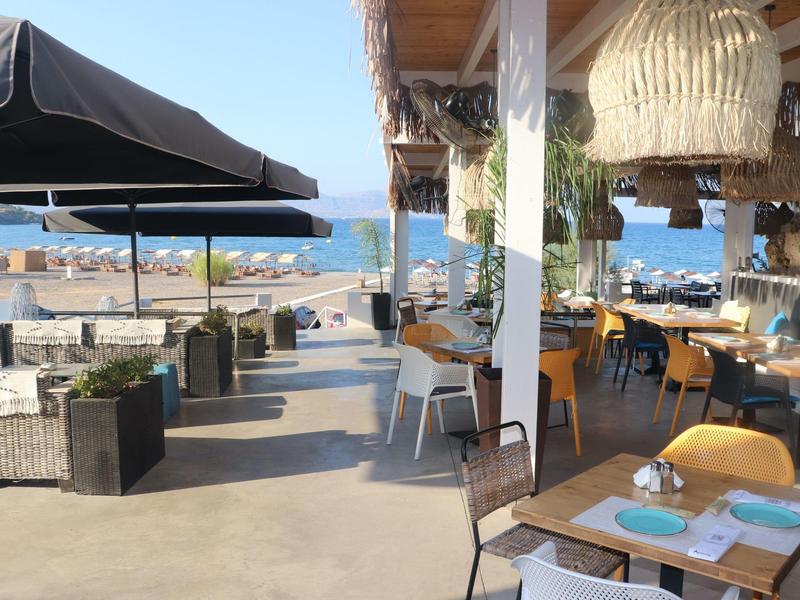 Ristorante all'aperto con vista sulla spiaggia e sul mare in una giornata di sole.