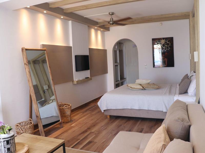 Camera d'hotel moderna con letto matrimoniale, divano e pavimento in legno.