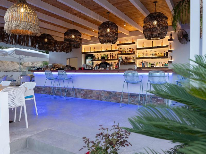 Area bar moderna con illuminazione elegante e atmosfera accogliente in un hotel.