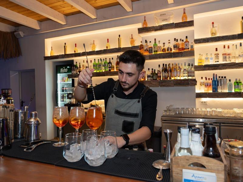 Un barista prepara diversi drink in eleganti bicchieri in un bar raffinato.