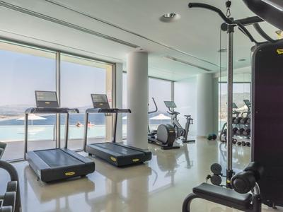 Siłownia z bieżniami, rowerami stacjonarnymi i sprzętem z widokiem na morze.