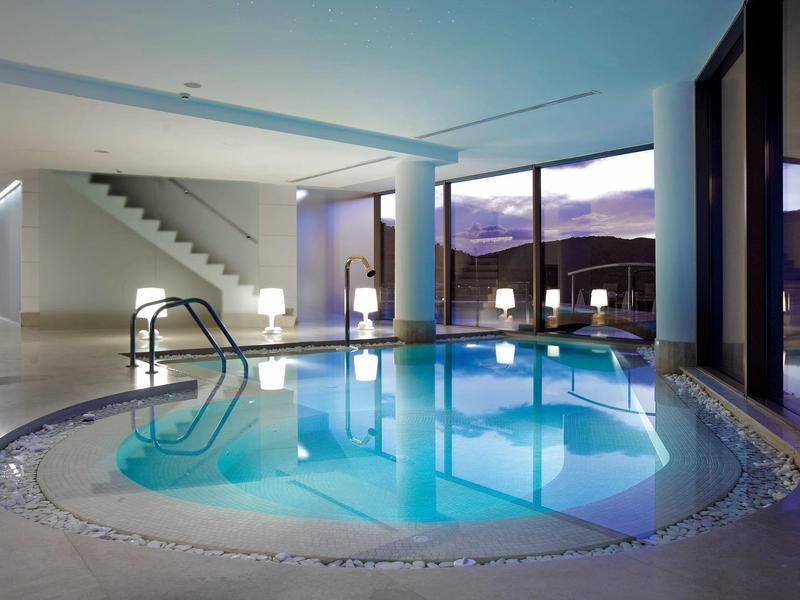 Moderner Innenpool in elegantem Raum mit großen Fenstern und Bergblick.