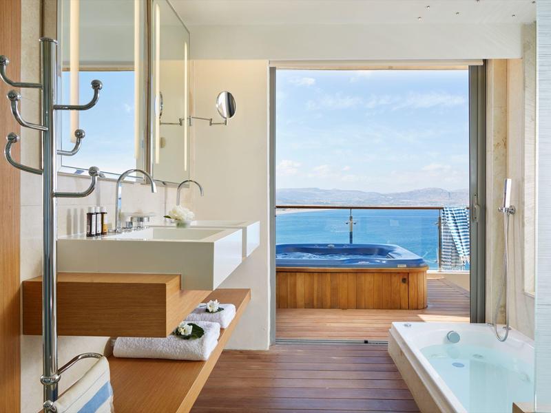 Elegantes Badezimmer mit Whirlpool und Meerblick durch große Fensterfront
