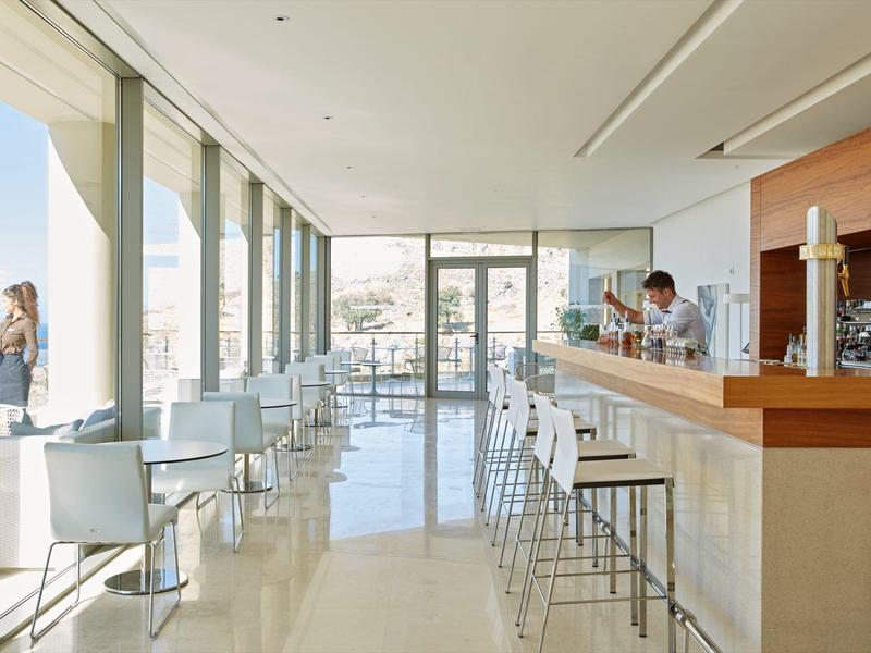 Helles, modernes Café mit weißen Stühlen und großem Fenster mit Blick auf die Stadt.