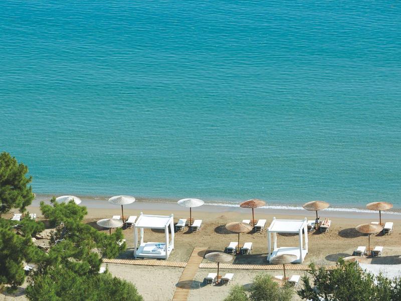 Strand mit weißen Sonnenschirmen und Betten am klaren blauen Meer
