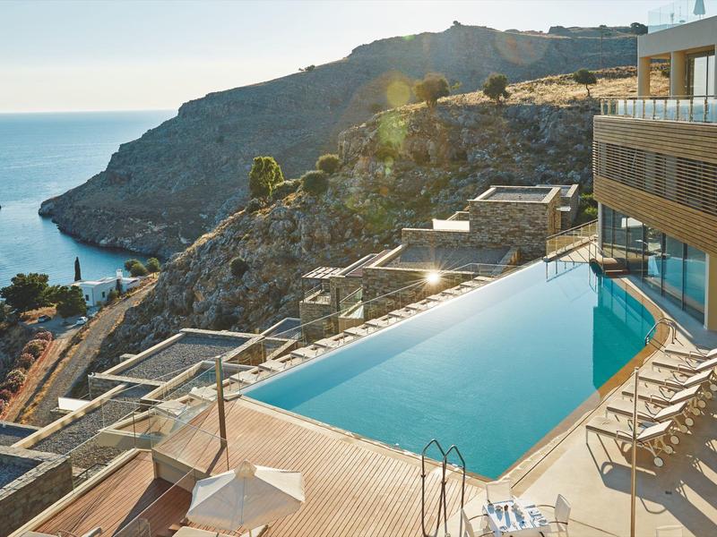 Infinity-Pool mit Sonnenliegen und Meerblick an einer modernen Luxusunterkunft.