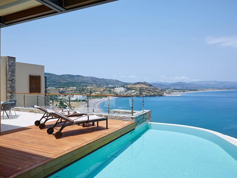 Infinity-Pool mit Sonnenliegen auf einer Terrasse mit Blick auf das Meer und die Berge.